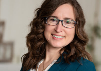 Headshot with teal jacket and glasses